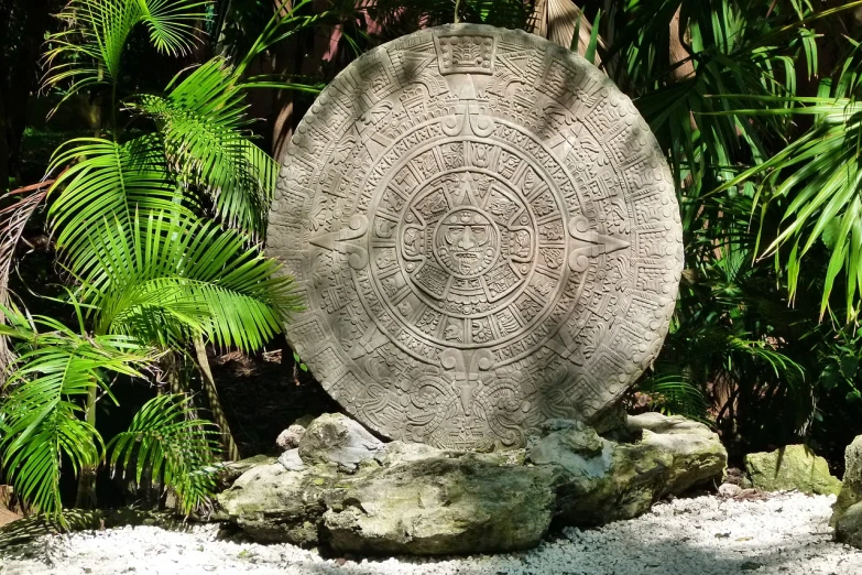 a stone sculpture sitting on top of a pile of rocks, a photo, aztec sun goddess, palm, beautiful ancient garden behind, ixions wheel