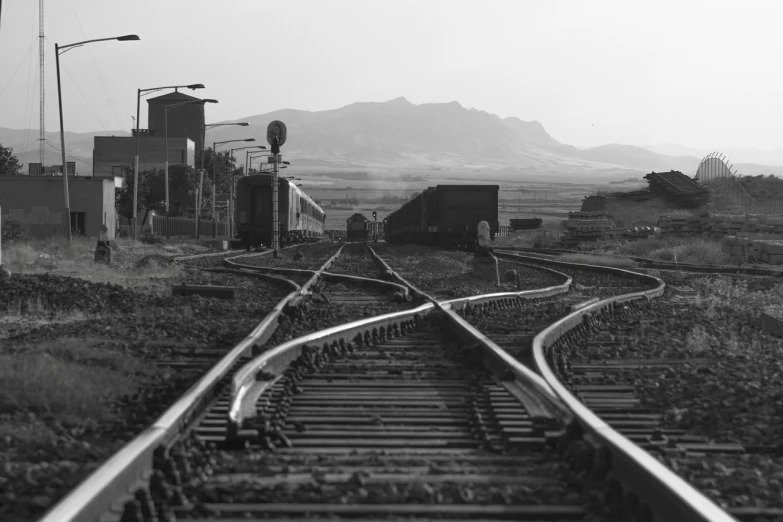 a black and white photo of a train track, by Dennis Ashbaugh, in chuquicamata, industrial setting, seen in the distance, maryport