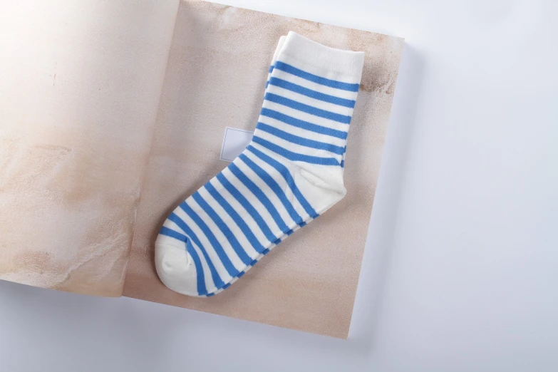 a blue and white striped sock sitting on top of a book, renaissance, product introduction photo, jinyiwei, 1 5 0 mm, productphoto