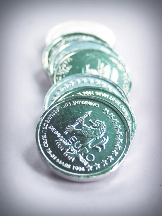 a bunch of coins sitting on top of each other, a tilt shift photo, inspired by János Saxon-Szász, flickr, dau-al-set, metalic green, intaglio style, cthulhu mythos, made out of shiny white metal