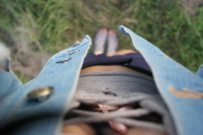 a person that is laying down in the grass, by Aleksander Gierymski, tumblr, mini jeans skirt, wideangle pov closeup, vest, very accurate photo