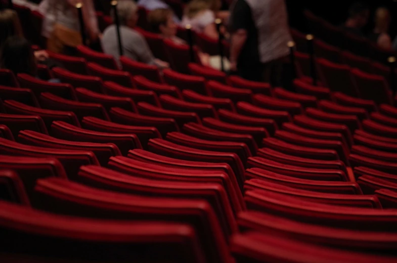 a bunch of red chairs sitting next to each other, a picture, pexels, figuration libre, khedival opera house, shallow depth of fielf, over-shoulder shot, broadway