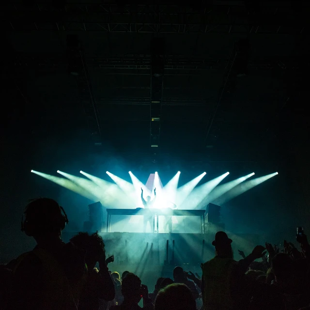 a group of people standing in front of a stage, pexels, light and space, crown of (((white lasers))), stock photo, dusty light, electronic music