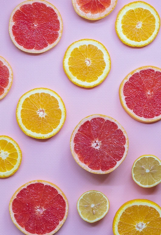 a group of grapefruits cut in half on a pink surface, by Anna Haifisch, pexels, process art, orange and orange slices, background image, lemons on the ground, wallpaper - 1 0 2 4