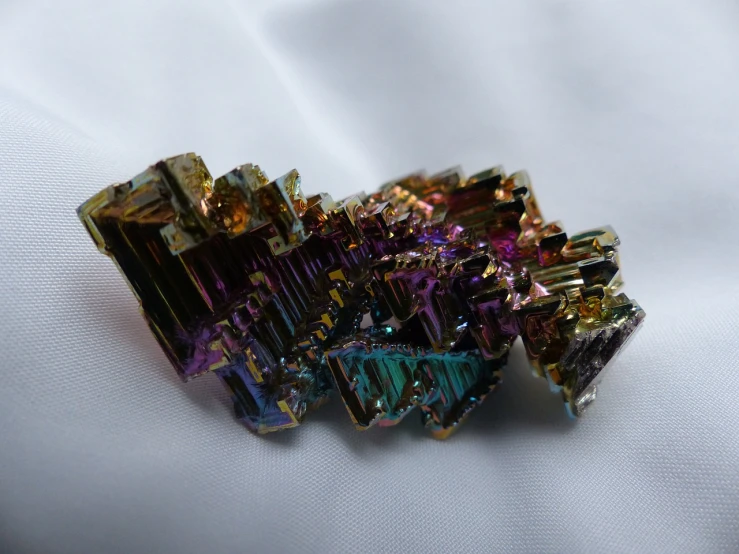 a bunch of crystals sitting on top of a white cloth, flickr, bismuth rainbow metal, green magenta and gold ”, side-view. highly detailed, crystal ruff