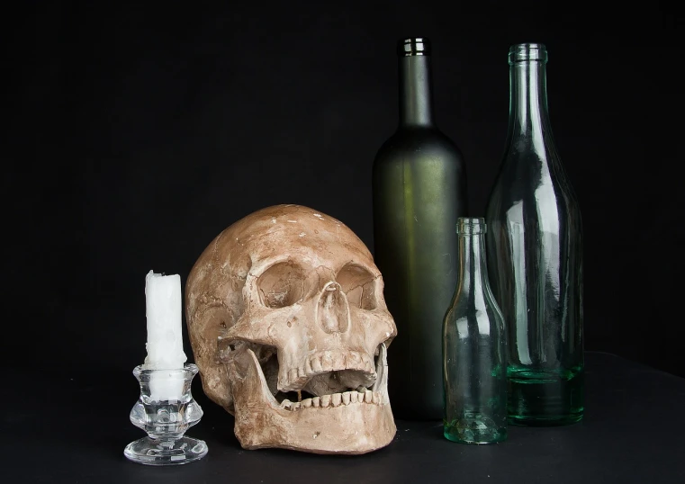 a skull sitting on top of a table next to bottles, inspired by Pieter Claesz, pixabay, miscellaneous objects, half body photo, set photo, close - up studio photo