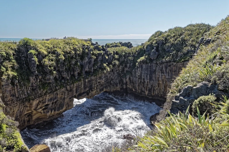 a large waterfall flowing through a lush green forest, a picture, pixabay, hurufiyya, sea storm and big waves cliffs, manuka, rock arches, portal 3