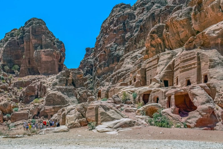 a group of people that are standing in the dirt, a cave painting, by Edward Ben Avram, pexels contest winner, les nabis, buildings carved out of stone, jordan, street view, 6 4 0