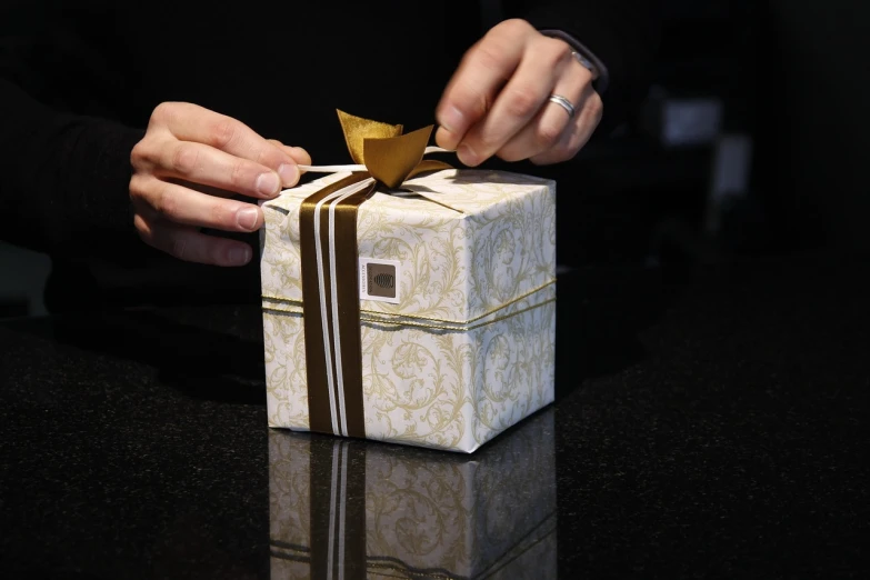 a close up of a person opening a gift box, by Adam Chmielowski, happening, ap photo, damask, golden ribbon, modern design