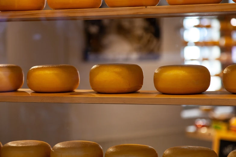 a shelf filled with lots of cheese on top of wooden shelves, a picture, purism, round format, smooth in the background, full of golden layers, dutch