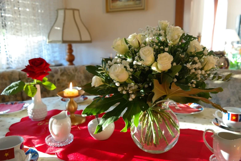 a vase filled with white flowers sitting on top of a table, by Maksimilijan Vanka, pixabay, white and red roses, on a sumptuous tablecloth, shades of gold display naturally, inside view