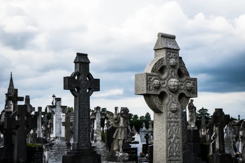 a cemetery filled with lots of tombstones under a cloudy sky, a tilt shift photo, gothic art, celtic knots, presidential cross, in a city with a rich history, tourist photo