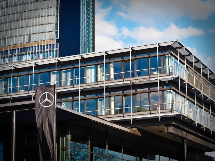 a clock on a pole in front of a building, by Thomas Häfner, pexels, bauhaus, mercedez benz, office building, mercedes, high res photo