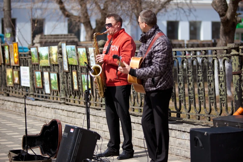 a couple of men standing next to each other on a sidewalk, a portrait, by Alexander Litovchenko, pixabay, plays music, during spring, on a stage, exhibition