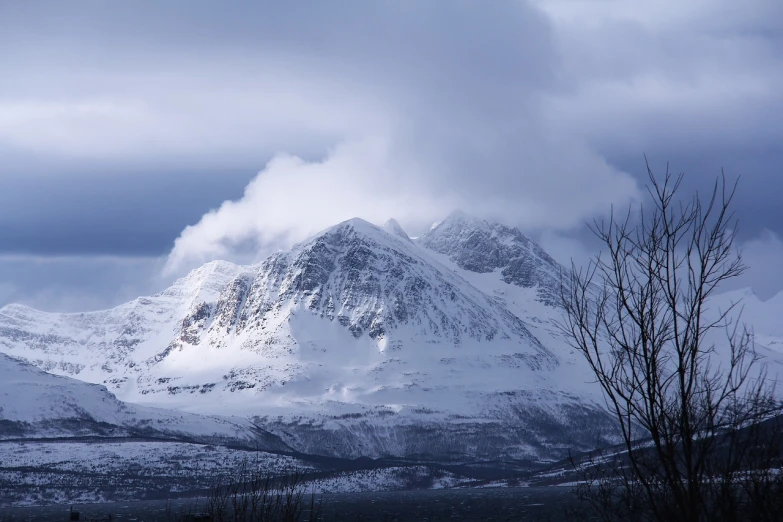 a mountain covered in snow under a cloudy sky, a photo, inspired by Johan Christian Dahl, flickr, nina tryggvadottir, telephoto shot, taken with my nikon d 3, misty mountains