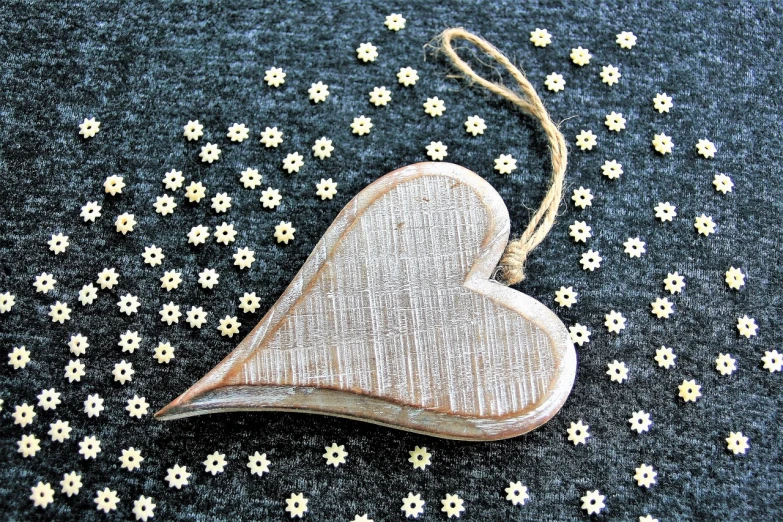 a wooden heart hanging on a string, trending on pixabay, folk art, sparkly, gray canvas, ivory carved ruff, above side view