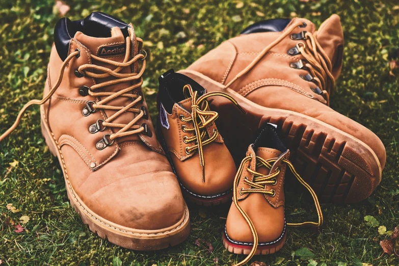 a pair of brown boots sitting on top of a lush green field, a picture, pexels, renaissance, happy family, different sizes, caramel. rugged, up close picture