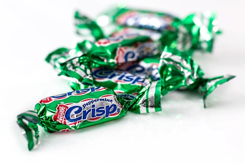 a pile of green candy sitting on top of a white table, a stock photo, inspired by Christen Købke, pepsi, productphoto, award - winning crisp details ”, mars candy bars