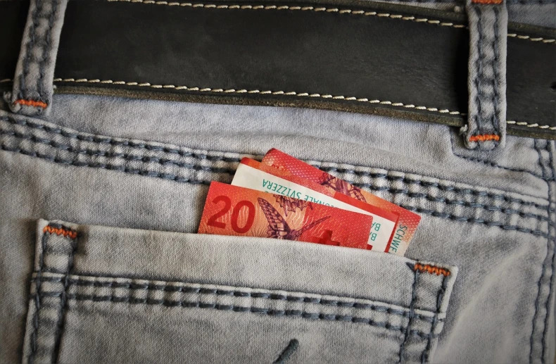 a pair of money sticking out of the back pocket of a pair of jeans, by Salomon van Abbé, happening, wellington, packshot, bag over the waist, swiss