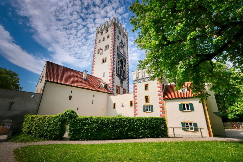 a tall building sitting next to a lush green field, a picture, by Oskar Lüthy, shutterstock, graffiti, fancy medieval architecture, white buildings with red roofs, elegant walkways between towers, 35mm wide angle photograph