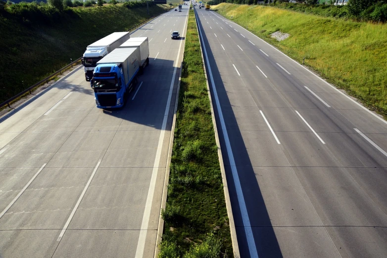 a blue truck driving down a highway next to a lush green hillside, by Hans Schwarz, flickr, infinitely long corridors, wide angle shot from above, warsaw, stock photo