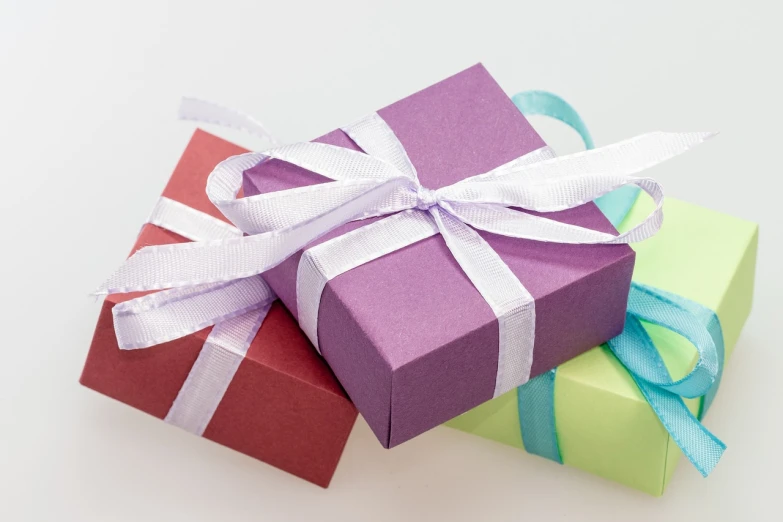 three colorful gift boxes tied with a white ribbon, pixabay, figuration libre, purple colour scheme, high angle close up shot, set against a white background, wide wide shot