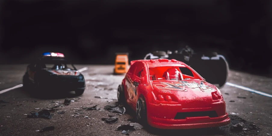 a couple of toy cars sitting on top of a road, by Richard Carline, pexels contest winner, 4k vertical wallpaper, total destruction, red theme, on a street race track