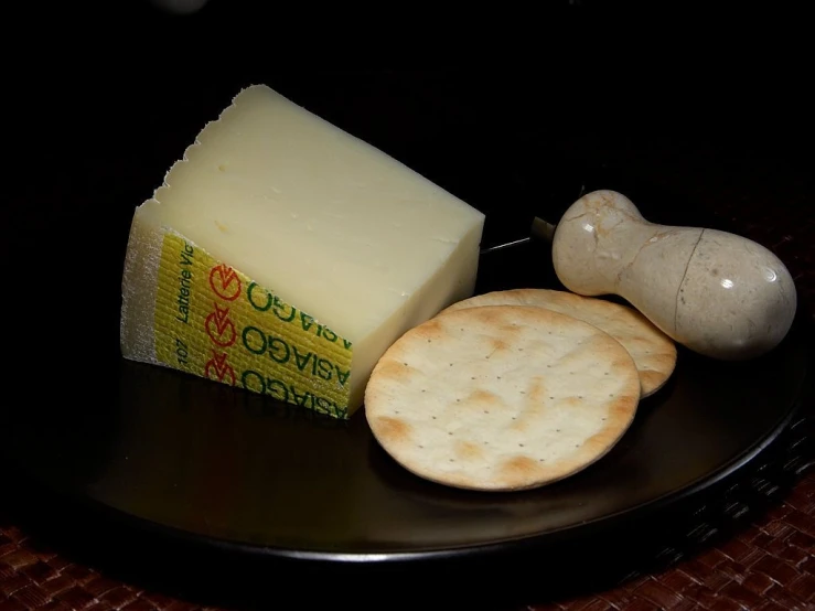 a black plate topped with crackers and cheese, a picture, inspired by Ceferí Olivé, dau-al-set, asencio, ivory, olbivion, indoor