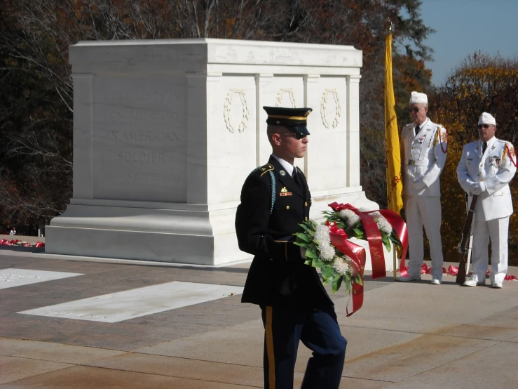 a man in uniform standing in front of a memorial, by Tom Carapic, flickr, standing over a tomb stone, inauguration, vine, person in foreground
