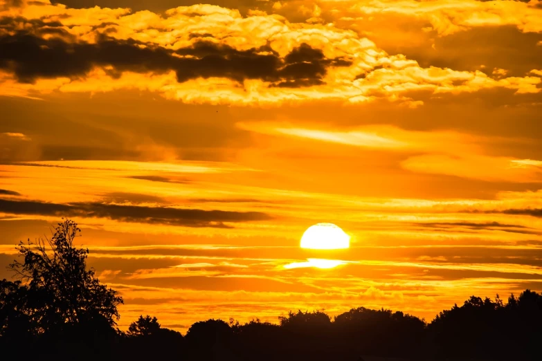 the sun is setting behind the clouds in the sky, a photo, by Hans Schwarz, shutterstock, shades of gold display naturally, hot summer day, silhouetted, shot on nikon z9