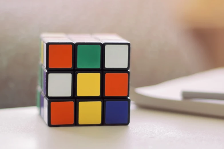 a rubik cube sitting on top of a table, inspired by Ernő Rubik, cubo-futurism, office cubicle background, retro colour, beautiful surroundings, square