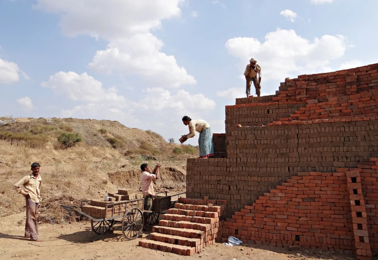 a group of men standing on top of a pile of bricks, a picture, by Hannah Tompkins, flickr, samikshavad, ziggurat, working, walls are made of dry wall, full shot photo