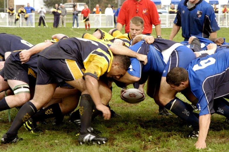 a group of men playing a game of rugby, by Ken Elias, flickr, blue and yellow, kneeling, athletic footage, ohio