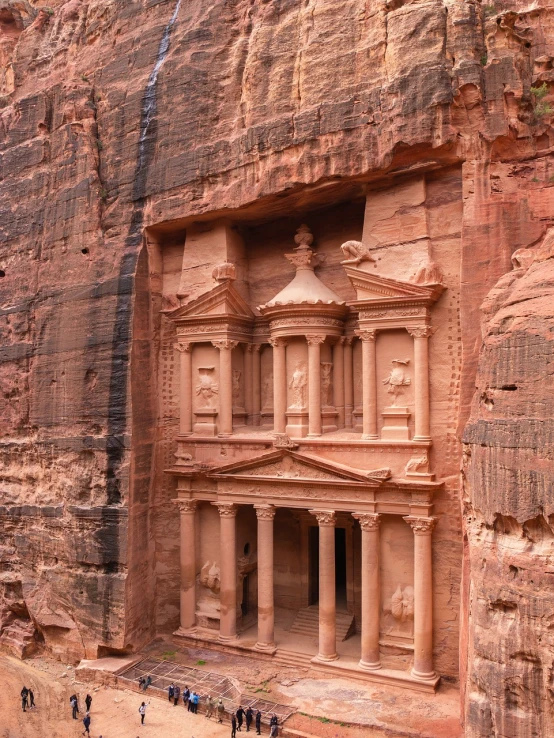 a group of people that are standing in front of a building, a detailed matte painting, inspired by Antonín Chittussi, pexels contest winner, red sandstone natural sculptures, jordan, ancient monument waterfall, elaborate carved wood balconies