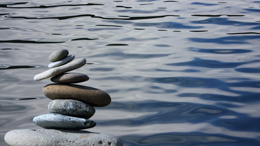 a stack of rocks sitting on top of a body of water, inspired by Saitō Kiyoshi, on the calm lake surface, istockphoto, taken with a pentax1000, ripples