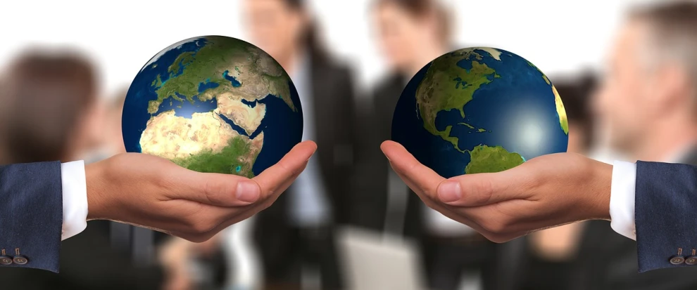 two hands holding a globe in front of a group of people, a picture, by Kurt Roesch, pixabay, bilateral symmetry, ad image, cleanest image, globes