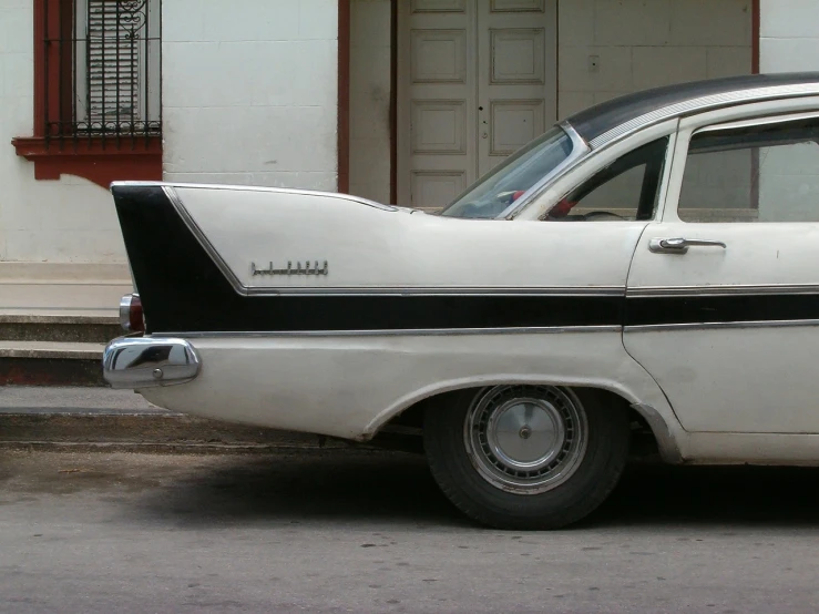 a white and black car parked in front of a building, by Ladrönn, flickr, tail fin, chihuahua, restored color, a pair of ribbed