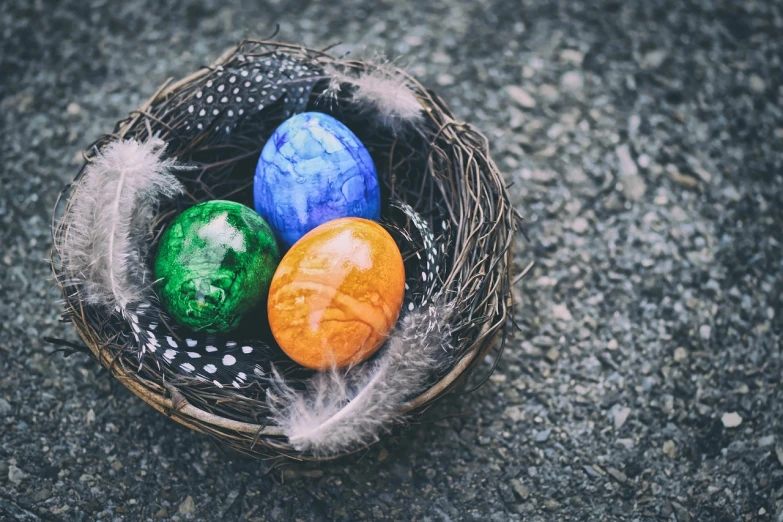 three eggs in a nest with feathers on the ground, a colorized photo, trending on pixabay, renaissance, coloured with lots of colour, 🚿🗝📝, with an easter basket, rock painting