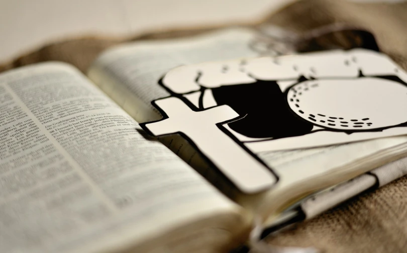 an open book sitting on top of a table, a digital rendering, by Thomas Häfner, unsplash, graffiti, shadow of the cross, die - cut sticker, mcbess illustration, closeup photo