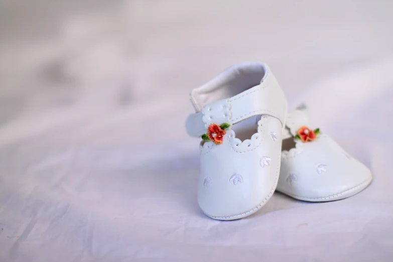 a pair of white baby shoes with flowers on them, a picture, 1285445247], toy photo, white bed, high res photo