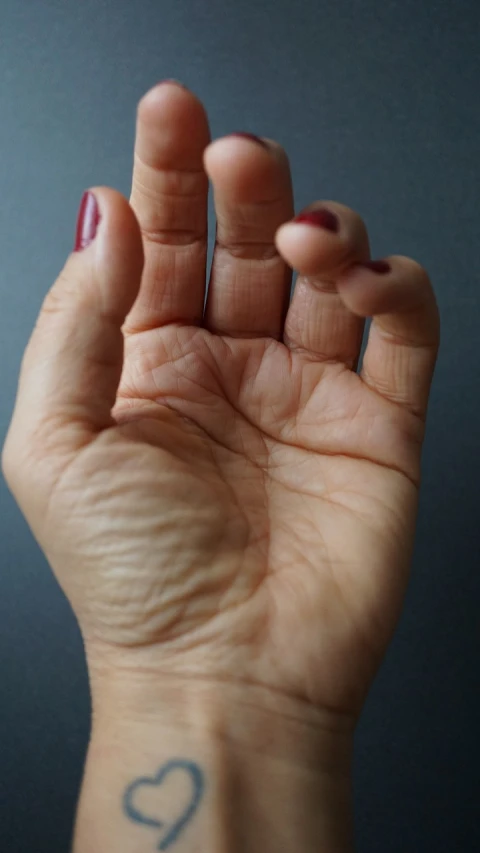 a woman's hand with a heart tattoo on it, a picture, by Jan Rustem, hyperrealism, lots of wrinkles, open palm, 3/4 view from below, kintsugi