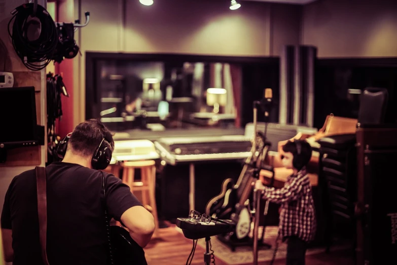 a man playing a guitar in a recording studio, a picture, by Mathias Kollros, pexels, realism, with a kid, behind the scenes photo, studio medium format photograph, instagram photo