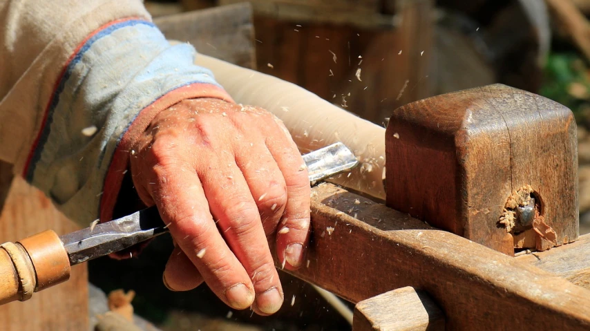 a person sharpes a piece of wood with a knife, by Edward Corbett, pexels, arts and crafts movement, wood carved chair, dust swirling, on a sunny day, beautiful hands