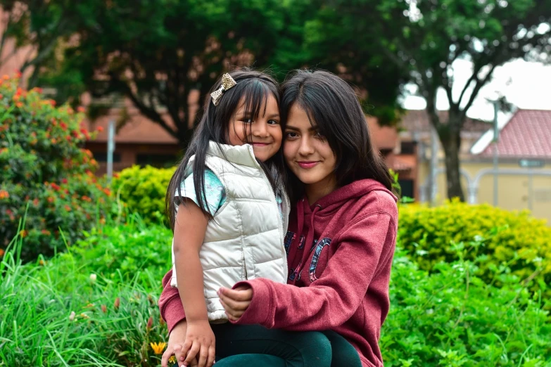 a woman sitting next to a little girl on a bench, a picture, pexels, quito school, avatar image, casual pose, hug, quechua!