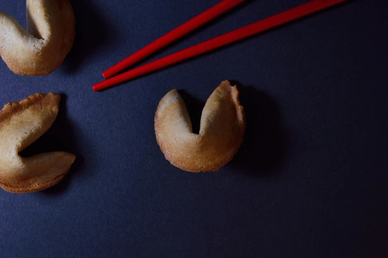 a close up of a fortune cookie with chopsticks, a picture, inspired by Mi Fu, unsplash, on black paper, food photo, red round nose, product introduction photo