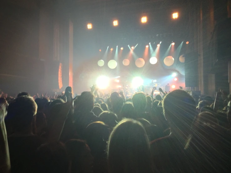 a group of people that are standing in front of a stage, a picture, by Matt Cavotta, tumblr, balls of light for eyes, concert hall, very hazy, year 2447