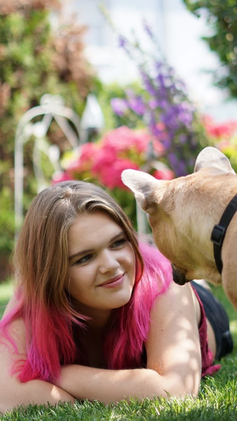 a woman laying in the grass with a dog, pink mohawk, a beautiful teen-aged girl, petting zoo, sitting in the rose garden