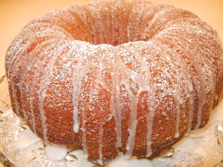 a bundt cake sitting on top of a glass plate, by Jim Nelson, powdered sugar, detailed zoom photo, glazed, round-cropped