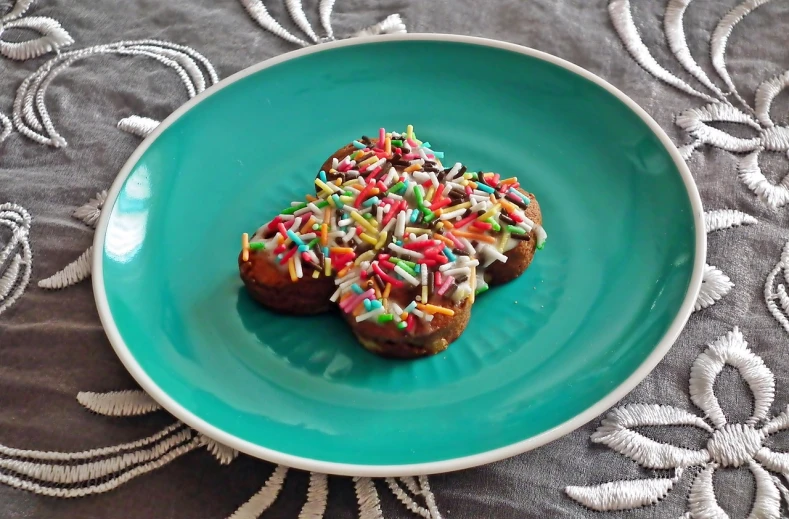 a blue plate topped with two donuts covered in sprinkles, inspired by Rudolf von Alt, flickr, renaissance, “ iron bark, clover, trio, multicolored glints