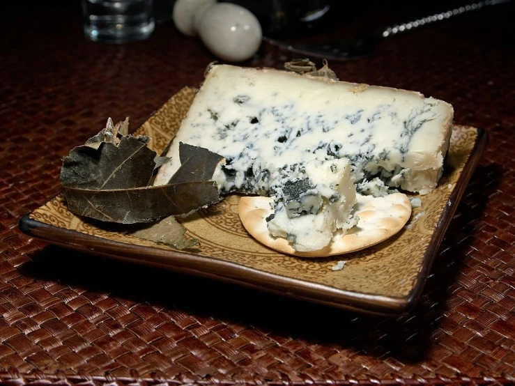 a plate of cheese and crackers on a table, by Juan Giménez, hurufiyya, blue fur with white spots, blue and black color scheme, mold, ivy's